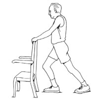 Side view of a man doing a warm-up and stretching exercise for his calves, by holding onto the back of a chair, stepping forward, and pushing the heel of the opposite heel down behind him.