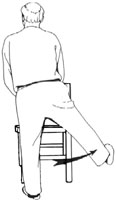 View of a man standing up from behind. He's holding a chair and swinging one leg to to the side and up in an arc. This is called a hip side kick.